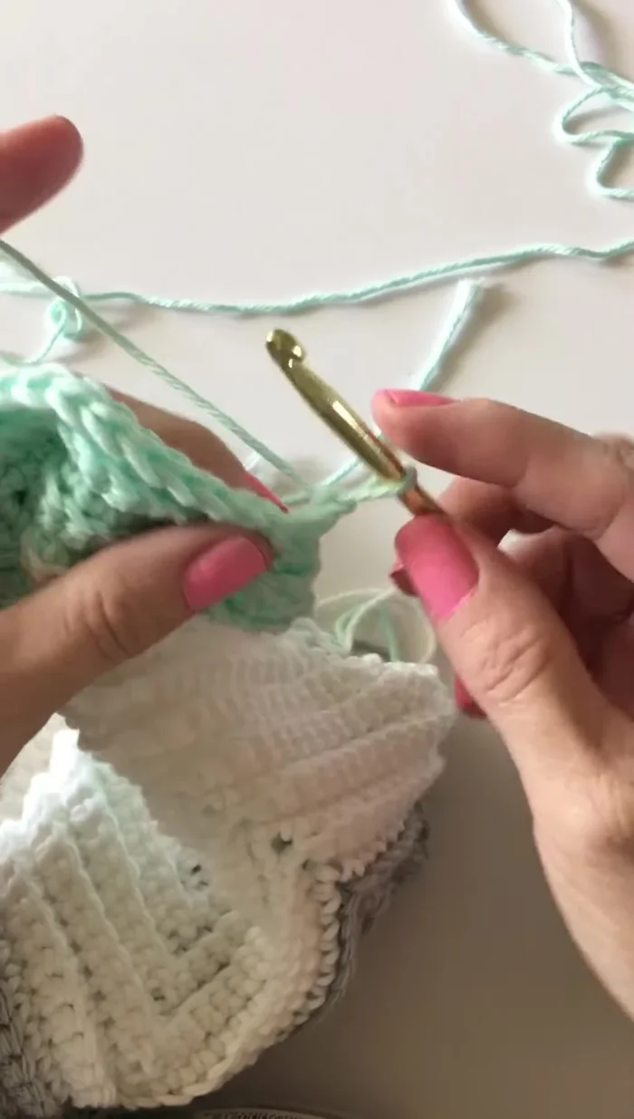 In den nächsten Zwischenraum gehen, eine Schlaufe hochziehen, wieder in den nächsten Zwischenraum gehen und eine Schlaufe hochziehen. Durch alle drei Schlaufen ziehen.