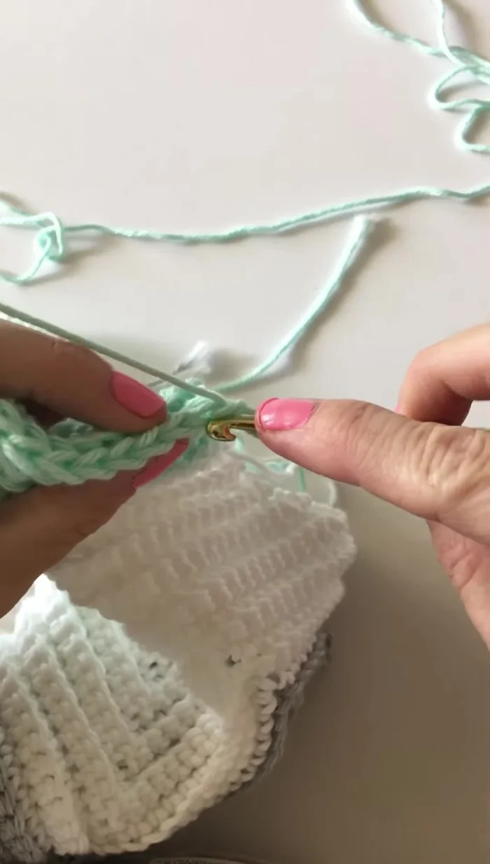 In den nächsten Zwischenraum gehen, eine Schlaufe hochziehen, wieder in den nächsten Zwischenraum gehen und eine Schlaufe hochziehen. Durch alle drei Schlaufen ziehen.